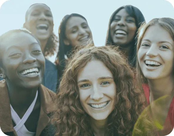Grupo diversificado de mulheres felizes e sorridentes reunidas ao ar livre, representando a união, a diversidade e a alegria.